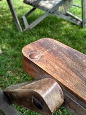 Close-up of a shiny tractor hitch pin resting on rustic wood.