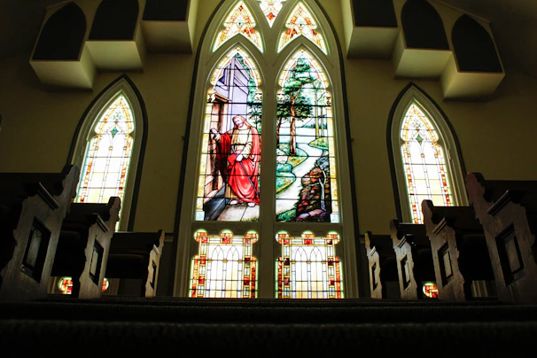 Pastor delivering a heartfelt message from the pulpit surrounded by vibrant stained glass windows