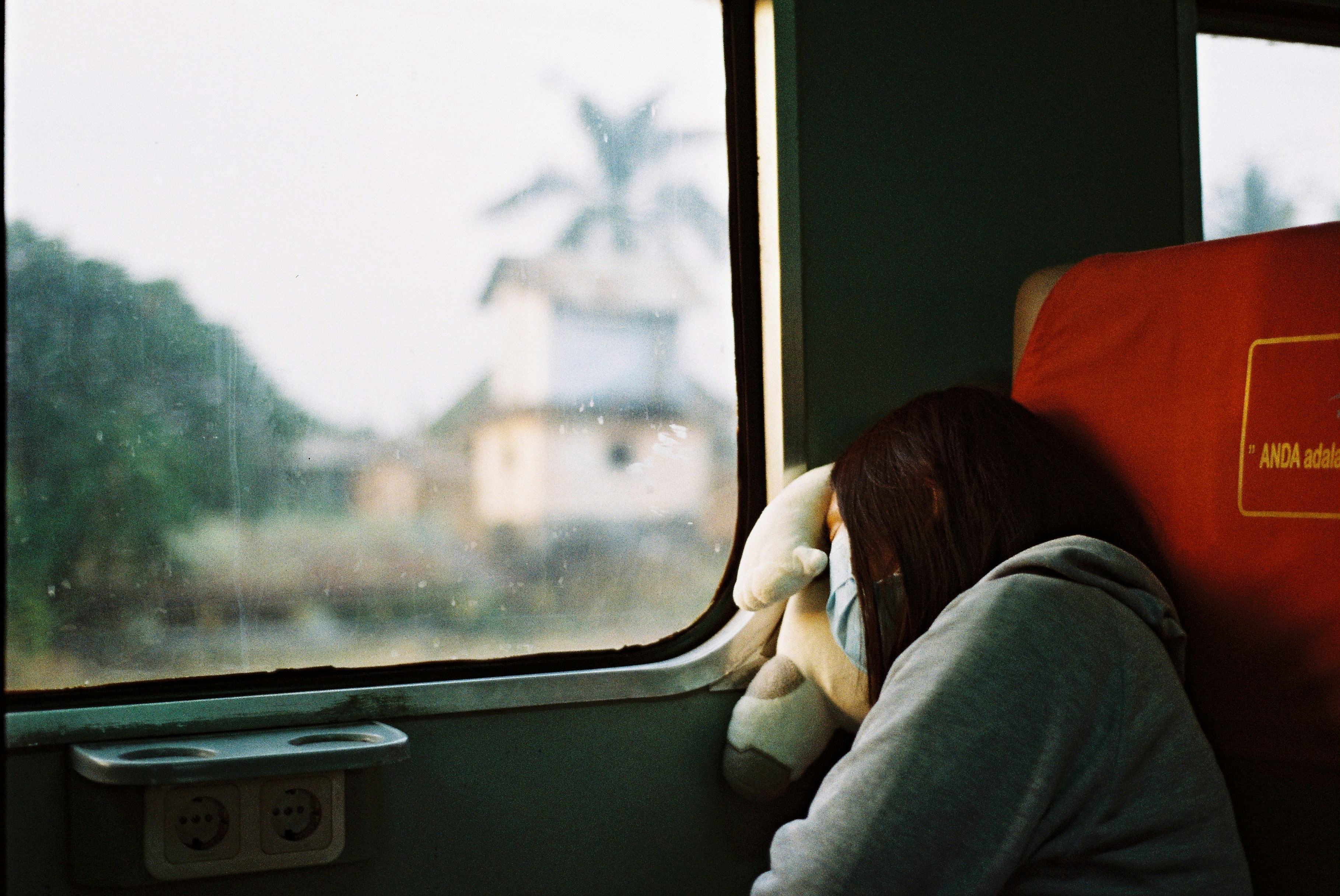woman in grey hoodie sleeping in a train with face mask, Indonesia bermimpi
