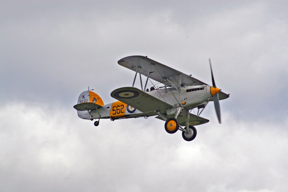 white and orange bi-plane in mid air