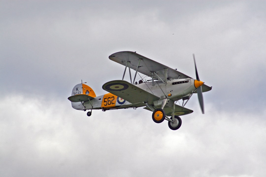 white and orange bi-plane in mid air, 1930s Fighter