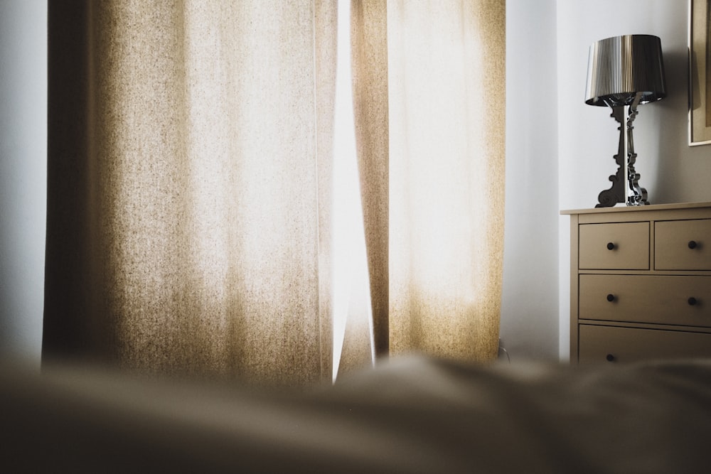 brown window curtain near dresser and table lamp