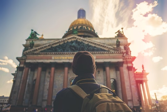 man staring gray and pink concrete building during daytime in St. Isaac's Cathedral Russia