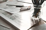 A collection of creative sketches and blueprints spread across a wooden desk.