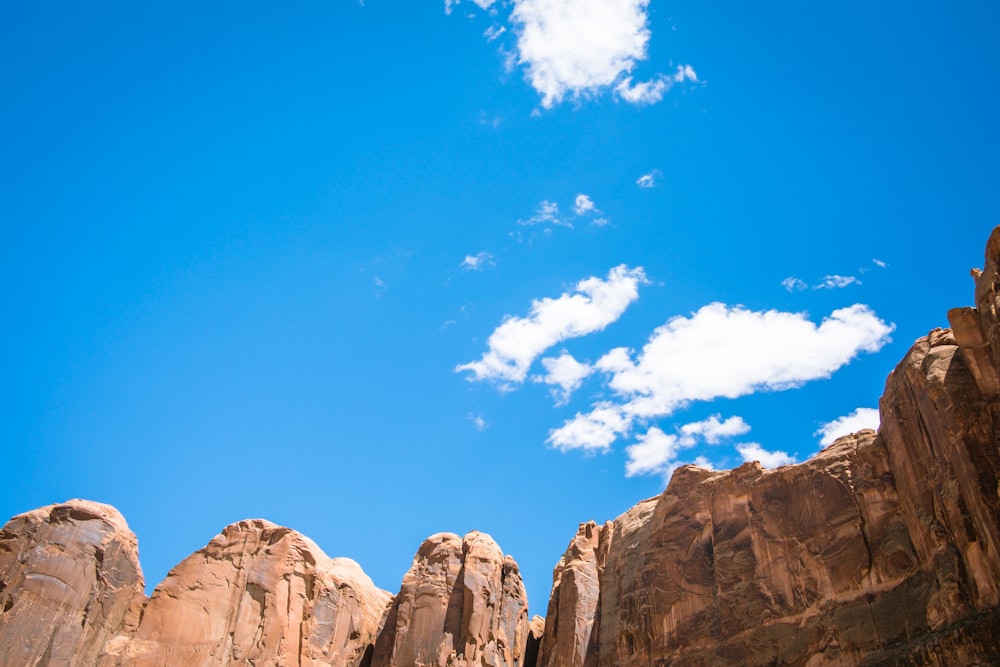 brown cliff under white and blue cloudy sky