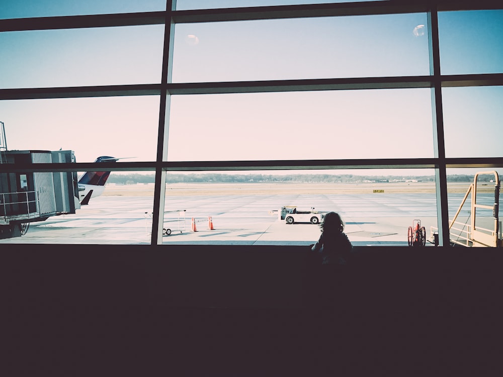 una persona che guarda fuori da una finestra in un aeroporto