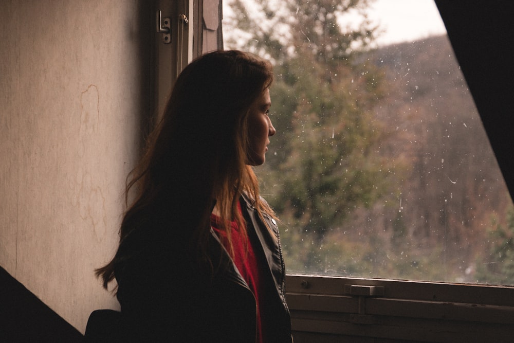 a woman standing in front of a window looking out