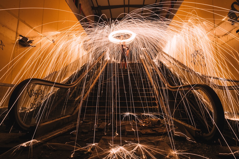 steel wool photography of man standing on stairs