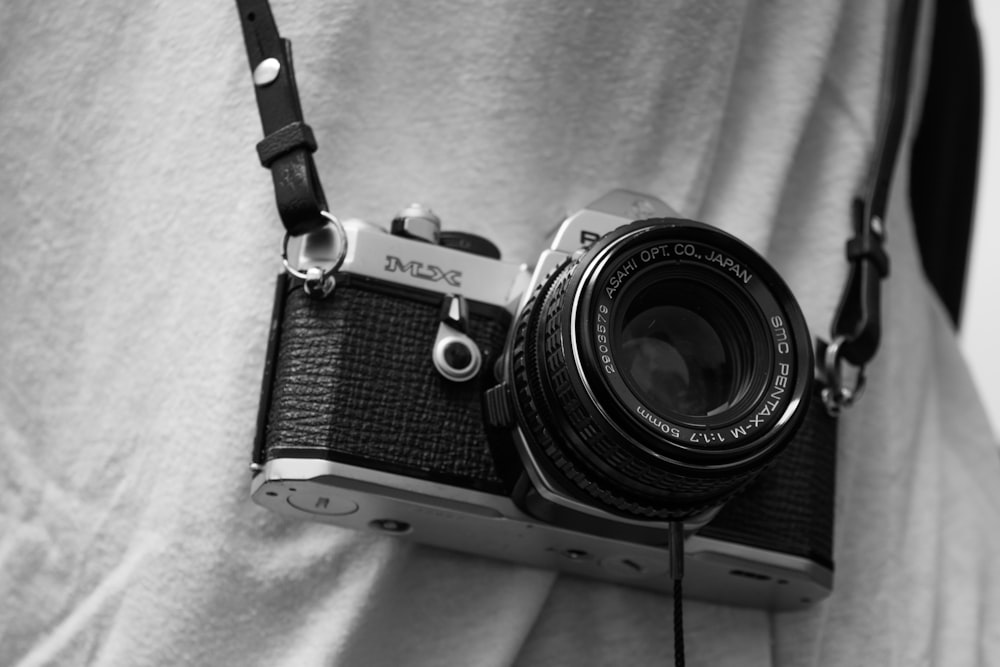 pessoa segurando câmera de filme preto e cinza com sling