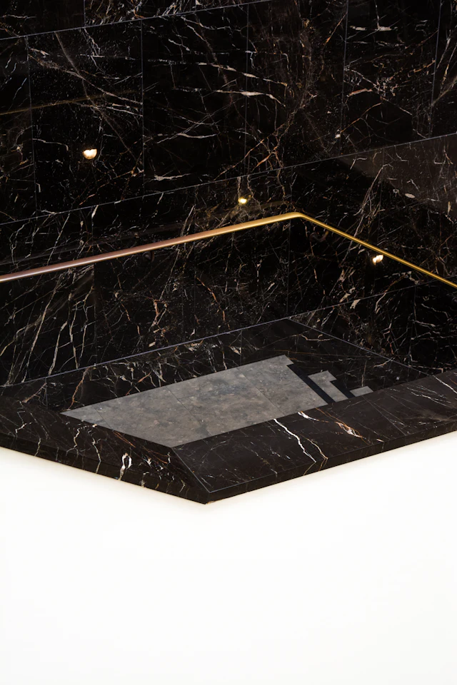 Black marble bathroom with a thin brass trim line