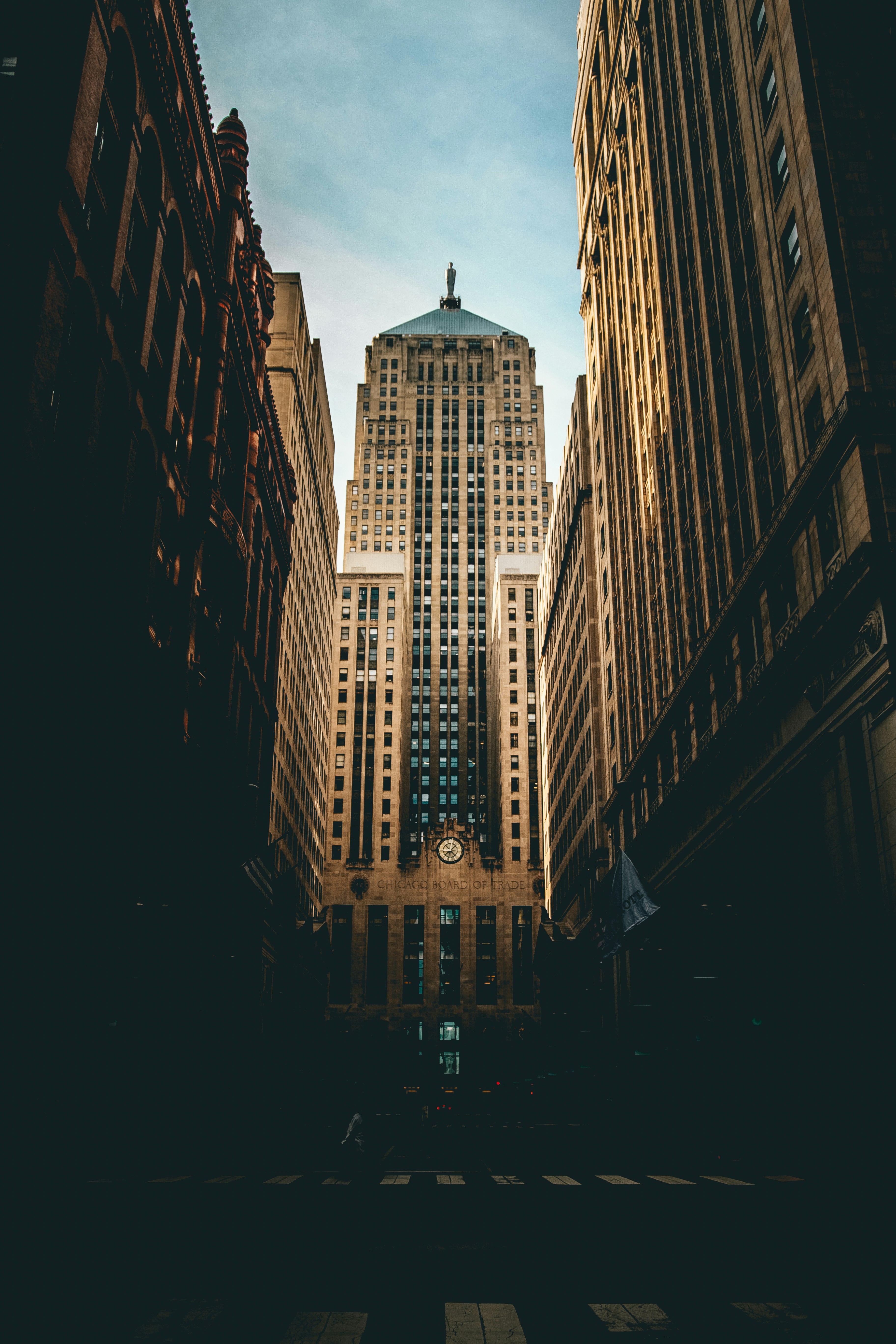 low angle photography of road straight to high-rise building under white and blue cloudy skies