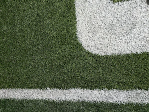 Technician carefully spreading infill material over artificial turf to improve durability.