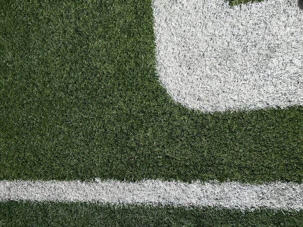 Detail of hands cutting and fitting artificial turf pieces precisely to create seamless joints.