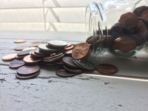 Silver coins spread out on a rustic wooden table catching the light softly.