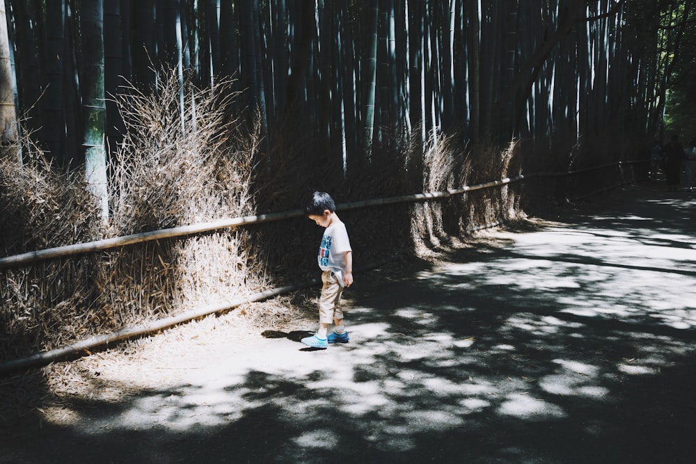 boy wearing white top standing on gray concrete floor