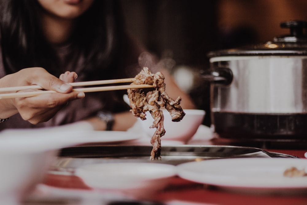 woman holding beige chopsticks