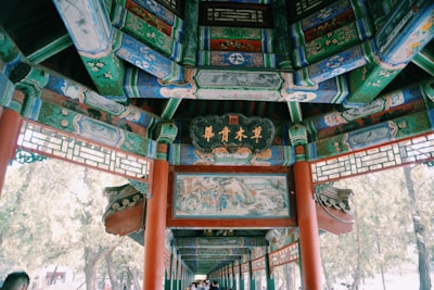 Intricate and colorful traditional architecture with ornate designs and calligraphy. The structure features a richly painted wooden ceiling with decorative panels and vibrant motifs.