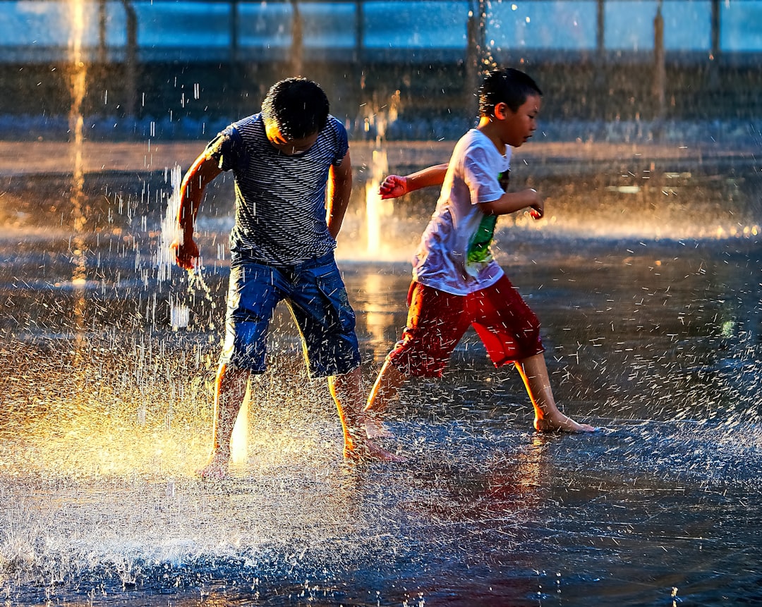 two boy standing in the rain during daytime