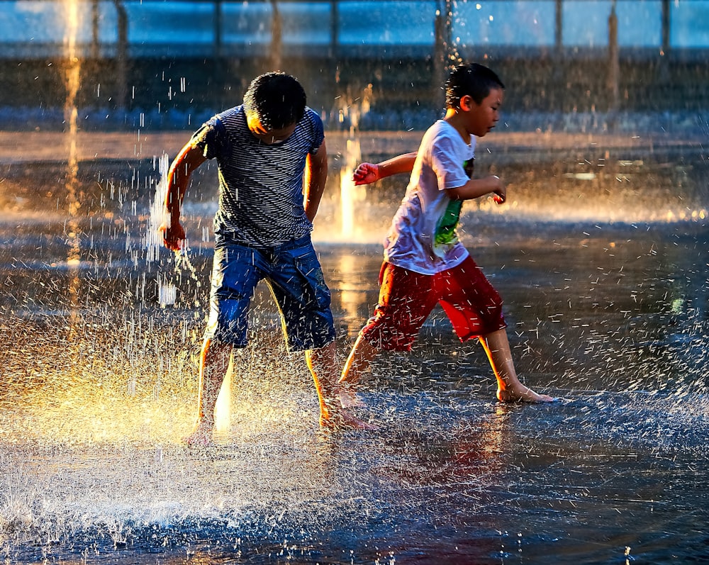 two boy standing in the rain during daytime