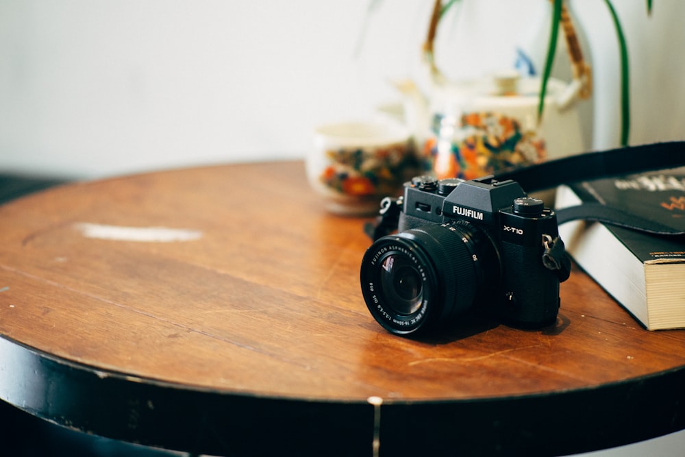 black DSLR camera on top of brown wooden table