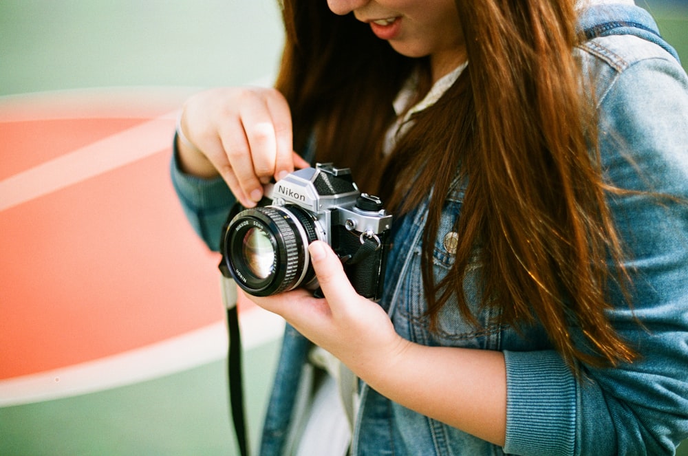 woman holding black bridge camera during daytime