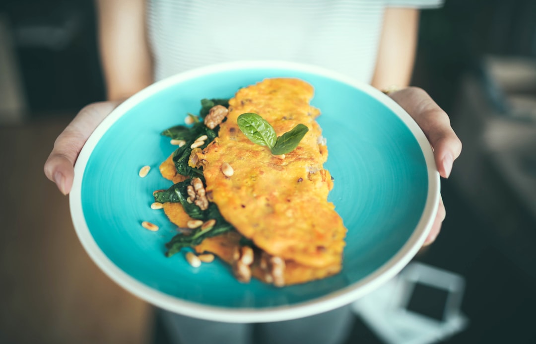 Woman holding an aquamarine plate with an omelette on it garnished with herbs