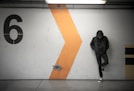 man leaning on white wall of the parking area