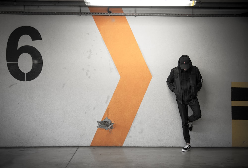 man leaning on white wall of the parking area