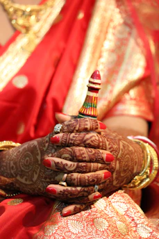 Close-up of a hand gently tying a vibrant bandhani saree, showcasing the intricate traditional dyeing technique.