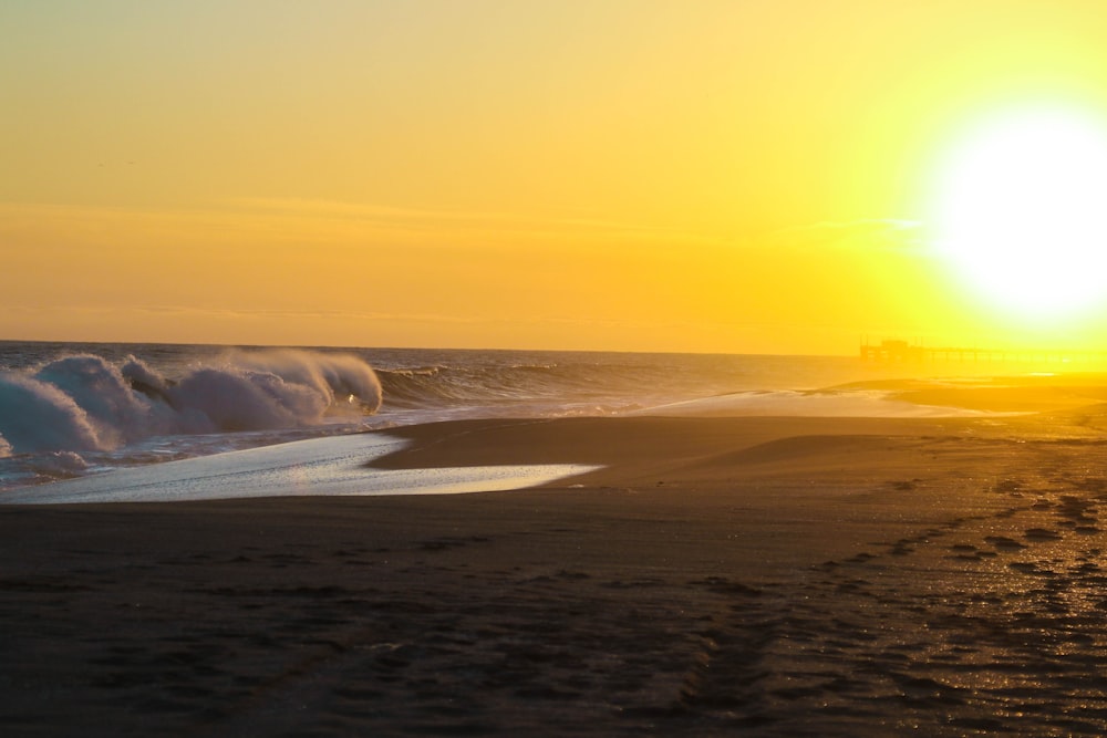 Praia de areia marrom durante o pôr do sol