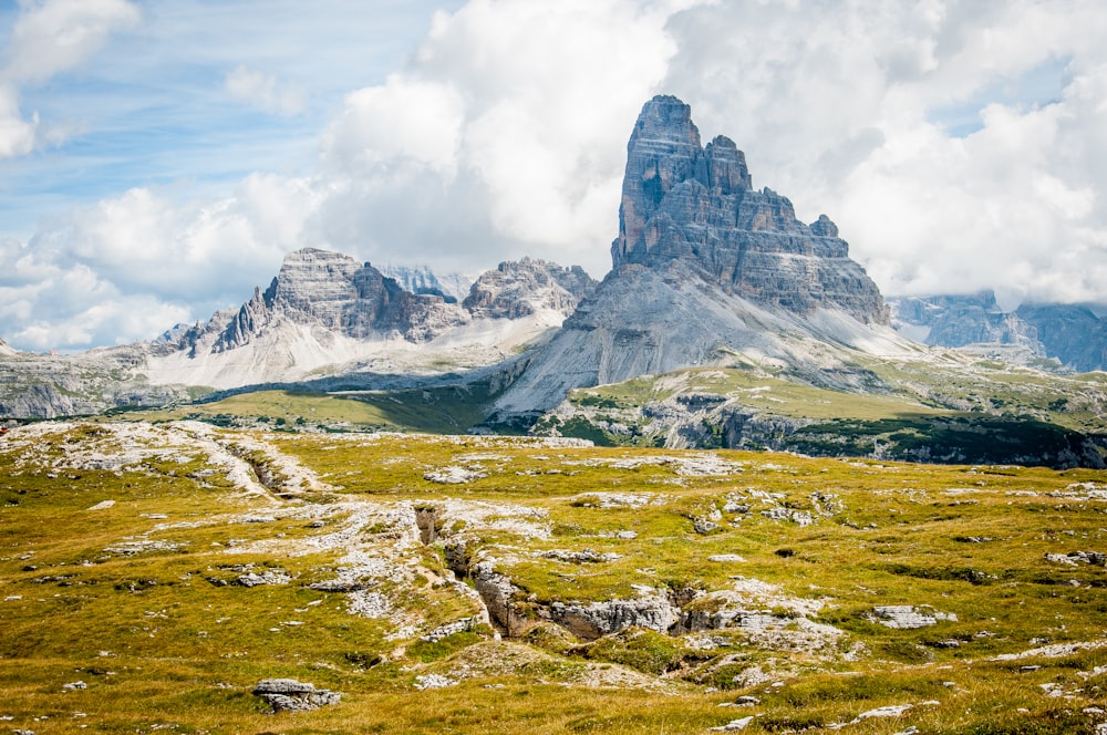 rock formation on wide field grass under cloudy blue sky during daytime