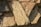 Large, rough-hewn stone slabs with an irregular arrangement. The surface displays a mix of warm earthy tones and is textured with visible striations and natural markings. Shadows are cast across the stones, adding depth to the composition.