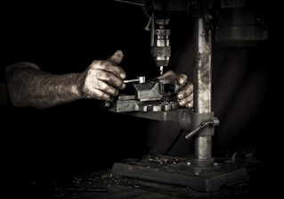 Close-up of hands calculating numbers with a metal workshop in the background.