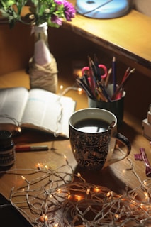 A serene workspace featuring a cozy desk adorned with colorful journals, art supplies, and a steaming cup of tea.