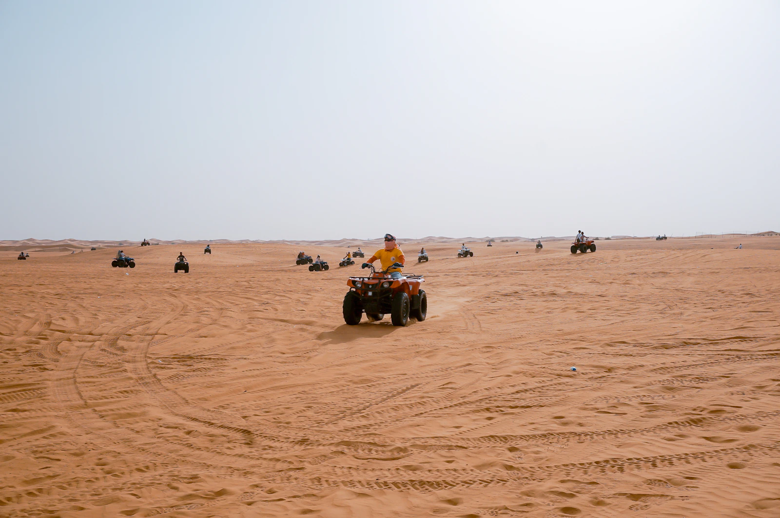 Quad bikes riding across flat sand in the Dubai desert
