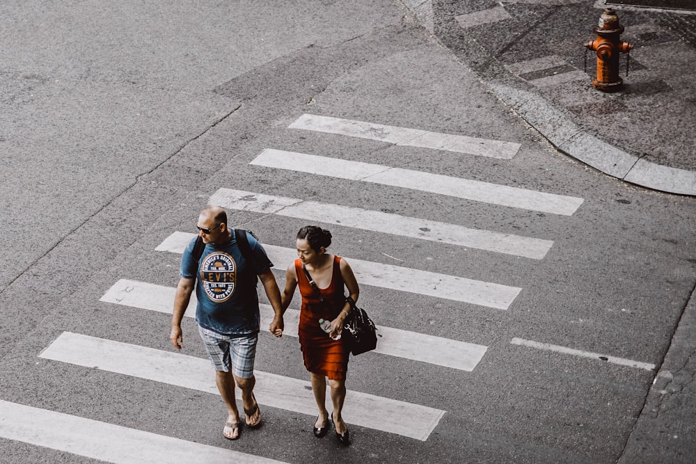 Hombre y mujer caminando en el carril peatonal durante el día