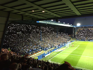 A focused soccer referee holding a VAR review tablet under stadium lights
