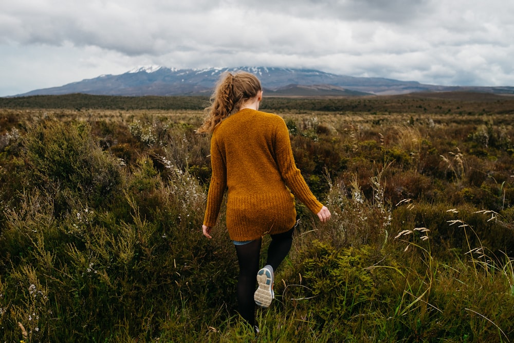 Mujer que camina en el campo de hierba bajo las nubes de estratocómulo