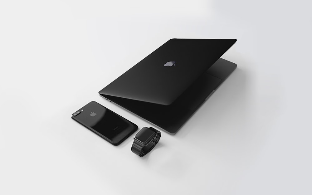 Macbook negro cerca del iPhone 7 Plus negro y Apple Watch negro