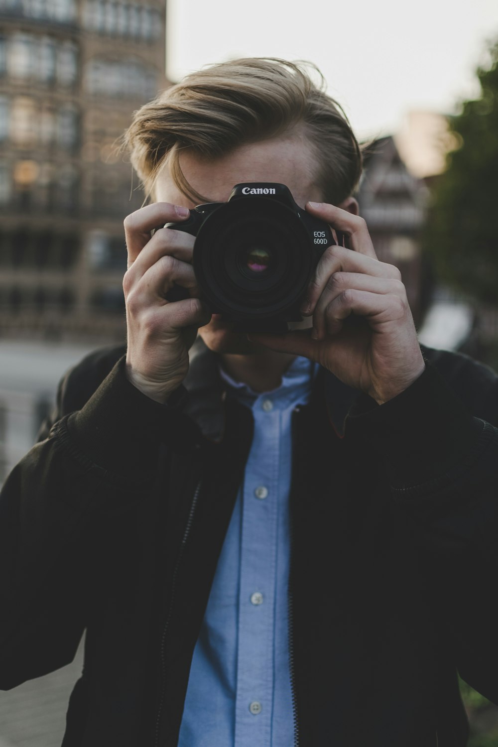 homem usando a câmera Canon EOS preta durante o dia