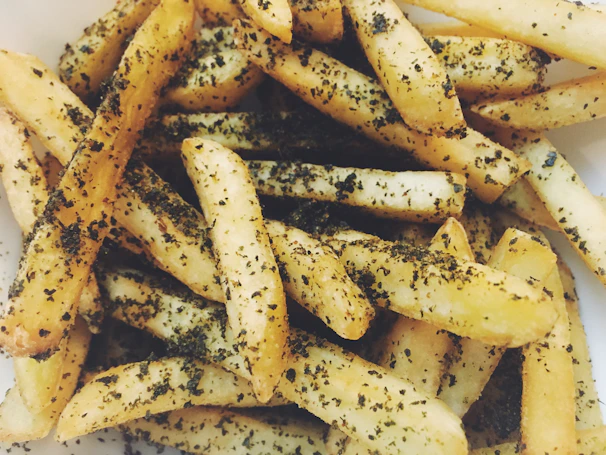 A basket overflowing with perfectly seasoned french fries, sprinkled with herbs.