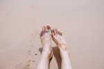 selective focus photography of feet with tattoo on sea sand