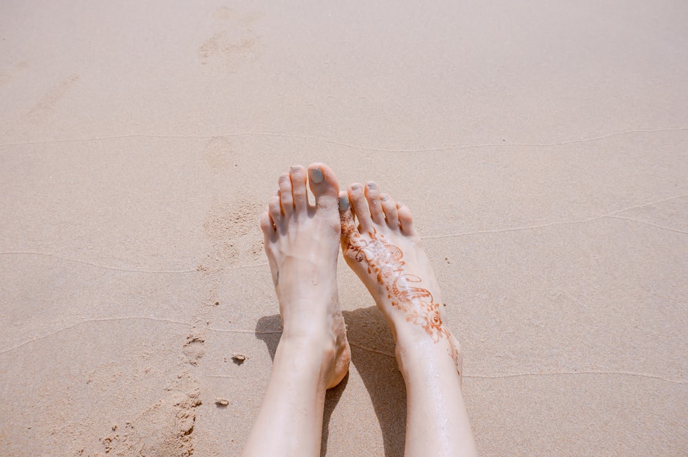 바다 모래에 문신이 있는 발의 선택적 초점 사진