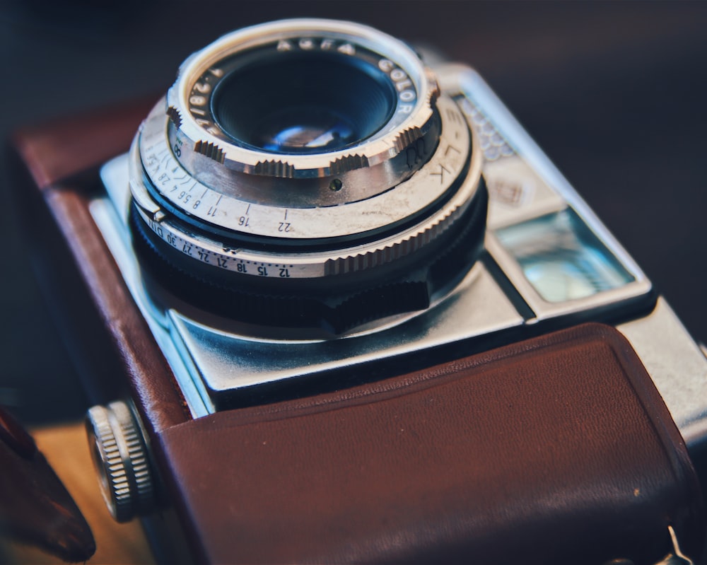 silver DSLR camera with brown leather case