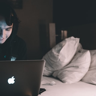 person using MacBook in bed