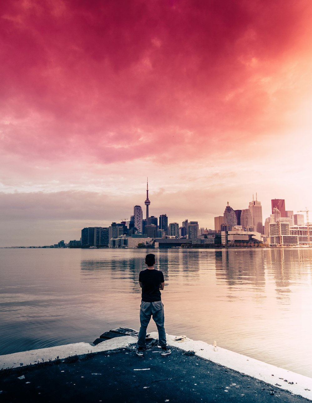 man standing facing body of water