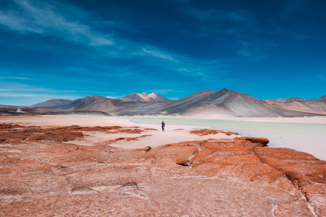 person walking in distance of mountain in Atacama Desert Chile