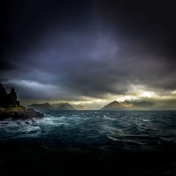 landscape photo of waters, mountains, and black clouds