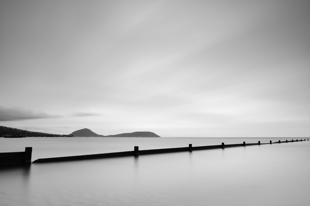 grayscale photo of body of water near mountain