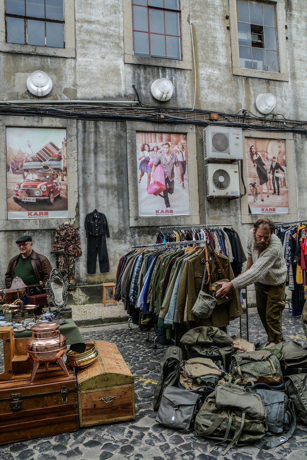 clothes and bags displayed on road near building during daytime